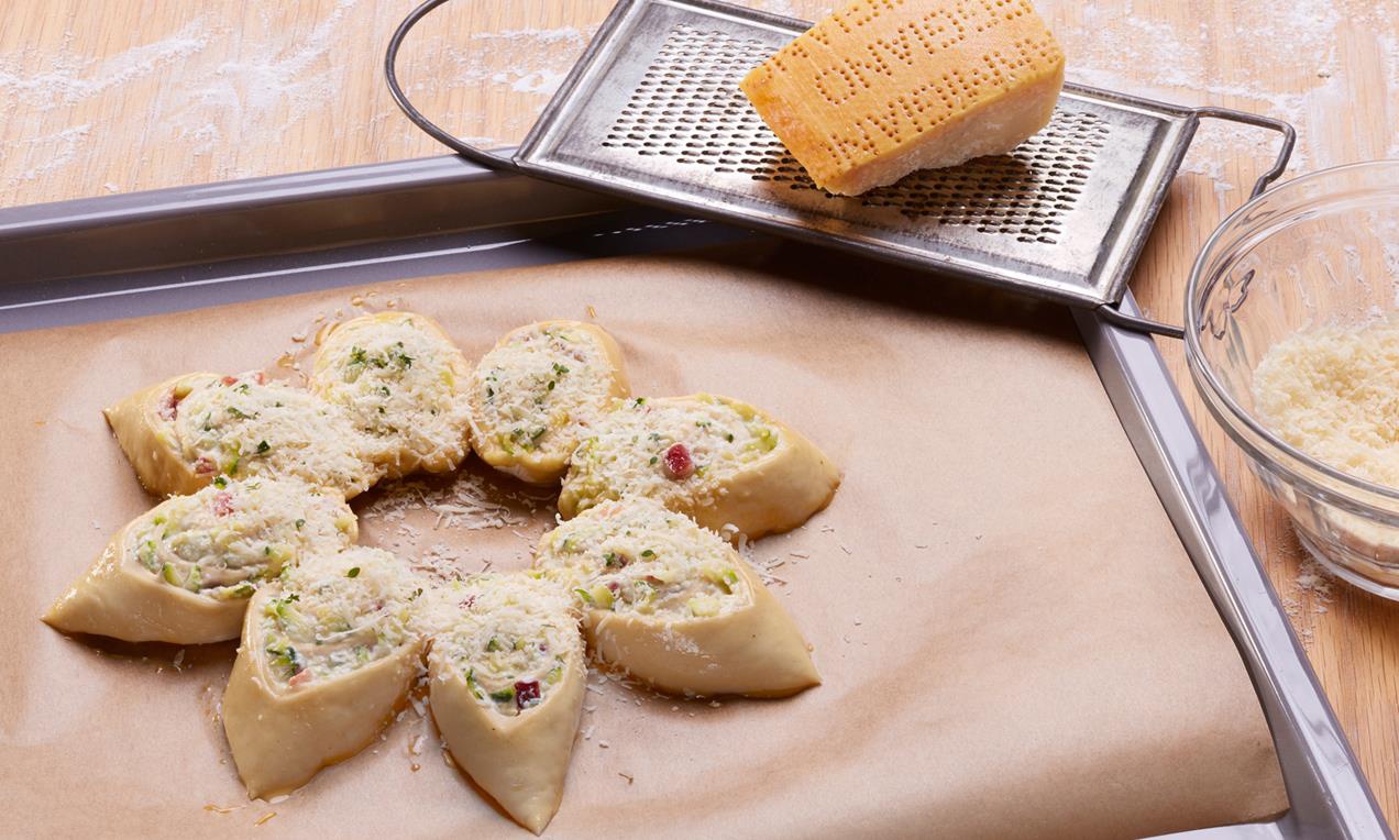 A Pikáns cukkinis virágok sütemény szeleteiből virágot formázunk a sütőpapíron.