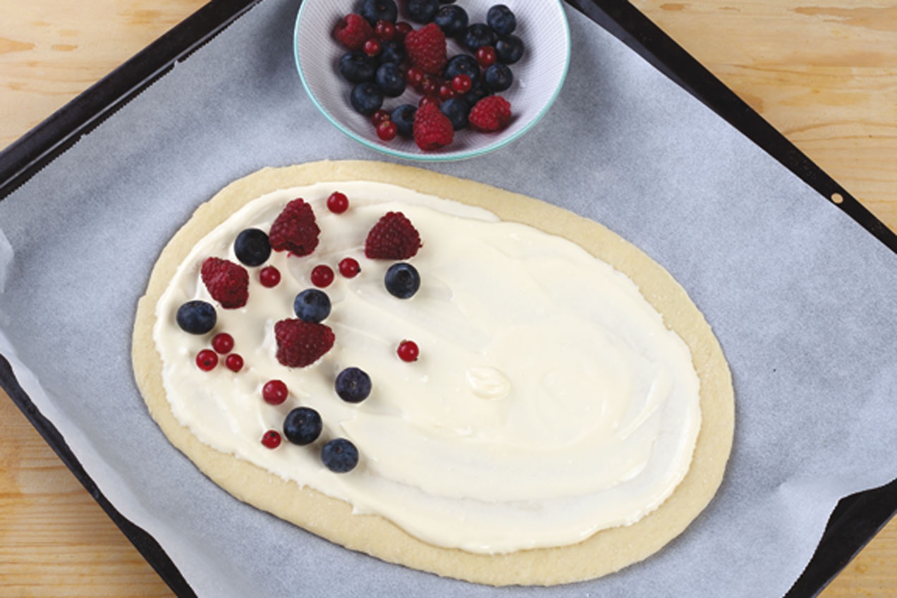 A bogyós gyümölcsöket egyenletesen eloszlatjuk a sütemény tetején.