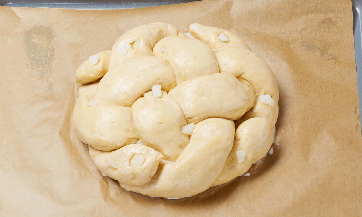 A precízen feltekert, csavart Édes fonott konty sütemény tetejét sütés előtt kenjük le tojásfehérjével.