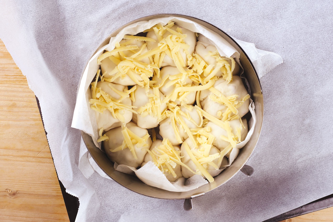 A töltött, feltekert Pikáns sonkás batyuk egymás mellé állítva kerülnek a sütőtálba.