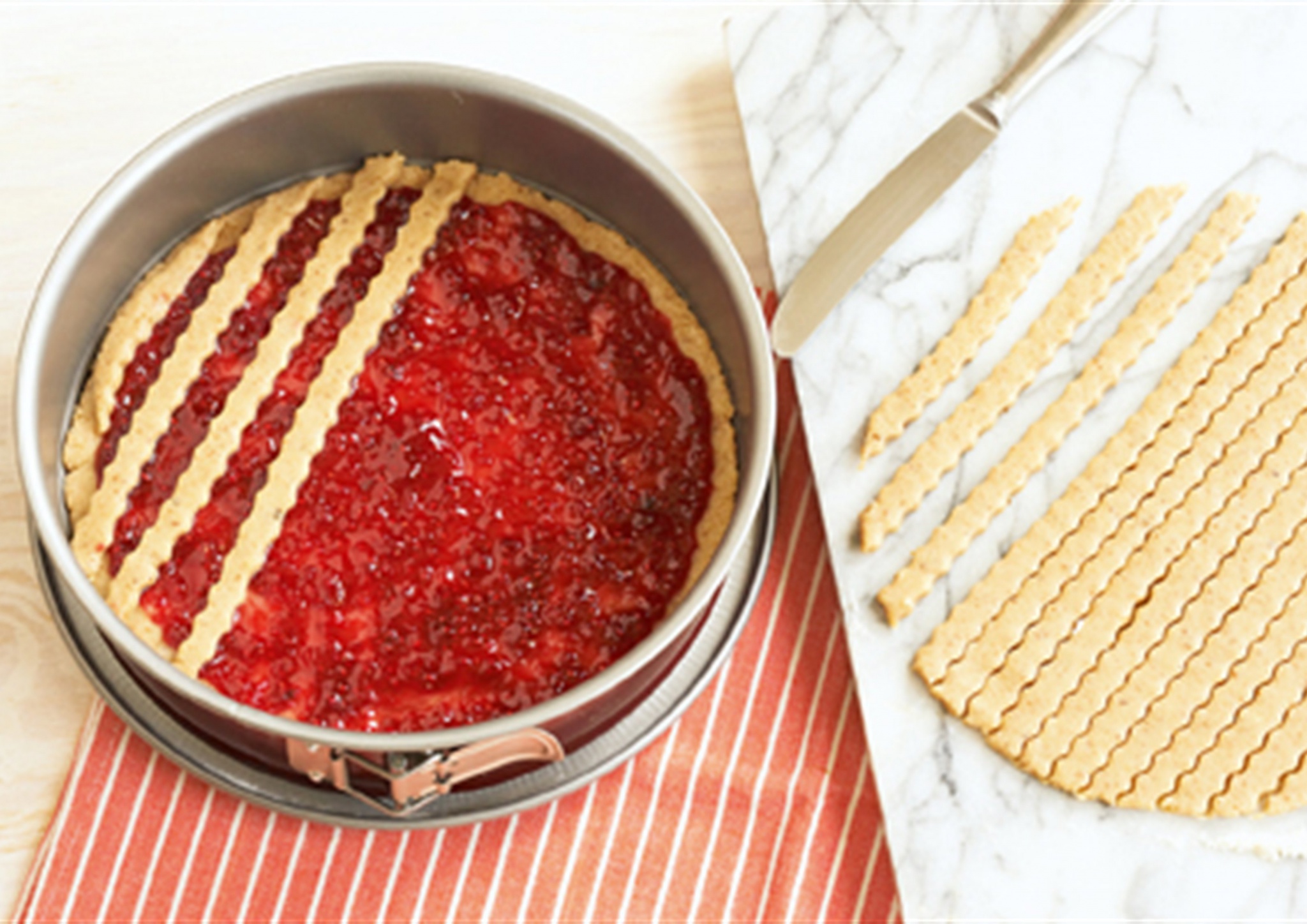 A felvágott csíkokból rácsot képezünk a Linzer torta tetején.