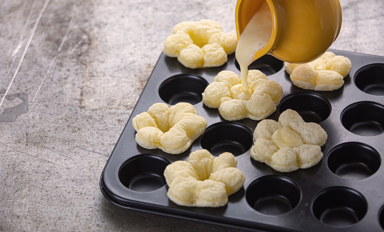 A muffinformába helyezett virágkehely formákat sütés előtt megtöltjük a krémmel.