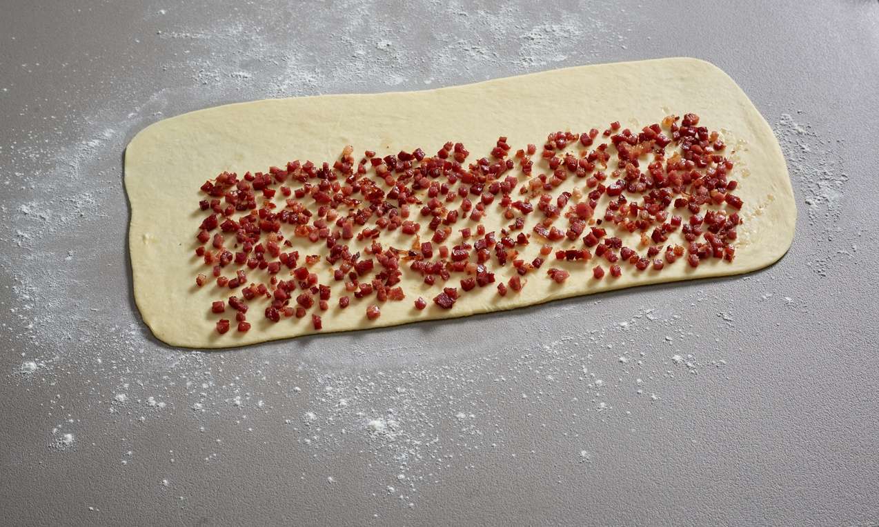 A Töltött házi bagett kinyújtott tésztájára halmozzuk a tölteléket.