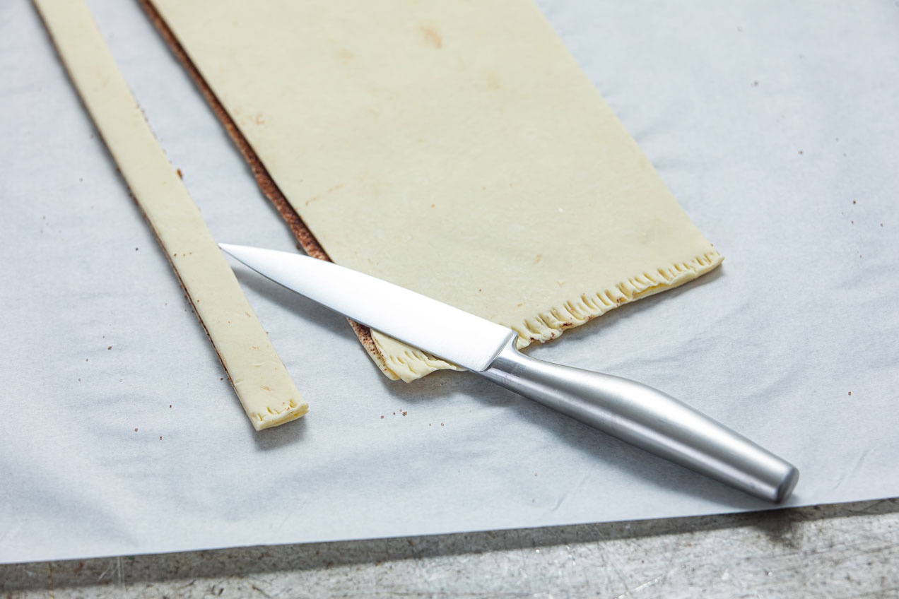 A kettéosztott és megkent, egymásra borított tésztát ollóval csíkokra vágjuk.