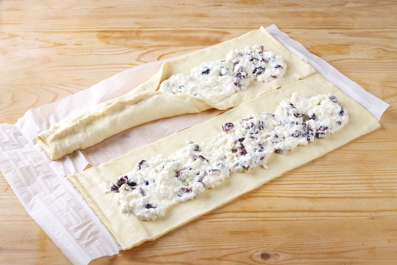 A Túrós-áfonyás koszorú kinyújtott tésztáját megtöltjük.