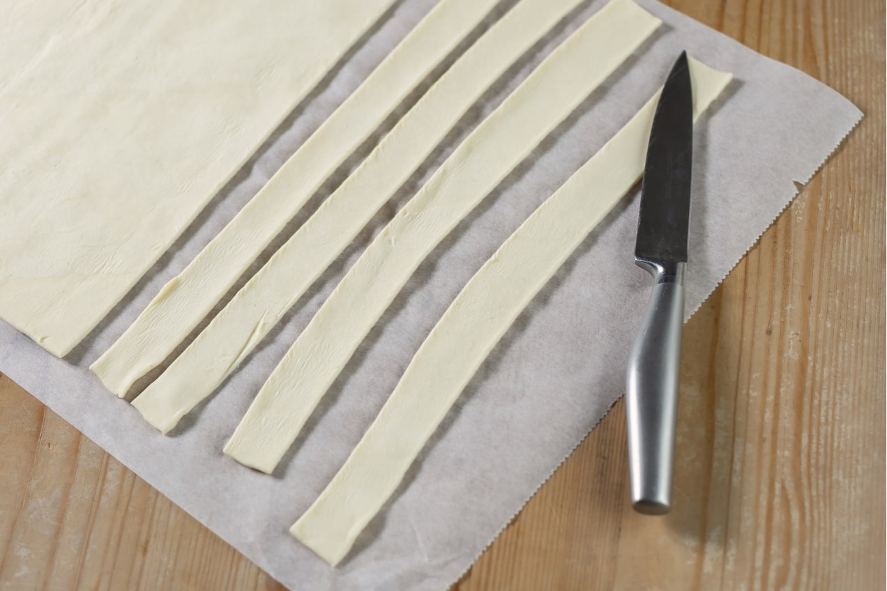 A Tavaszi roló sós leveles sütemény tésztáját csíkokra vágjuk.