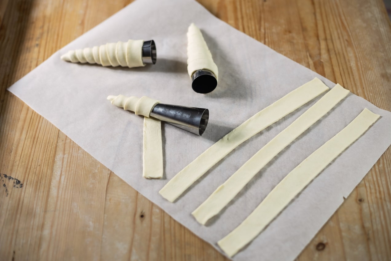 A sütemény tésztáját egyenként megtöltjük és kúp formájúra feltekerjük.