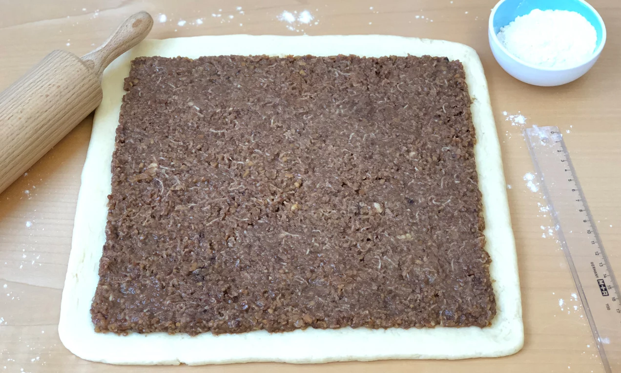 A Diós stollen kinyújtott tésztáját megkenjük a töltelékkel